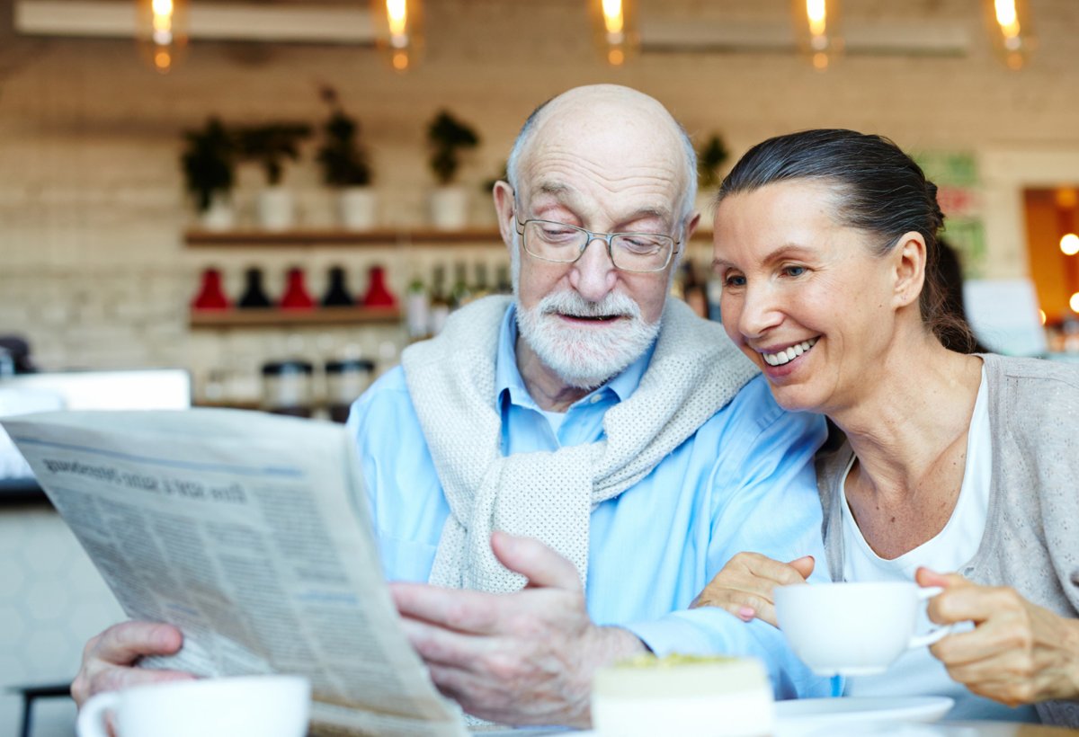 Elderly couple smiling at cafe — empowered by modern healthcare technology